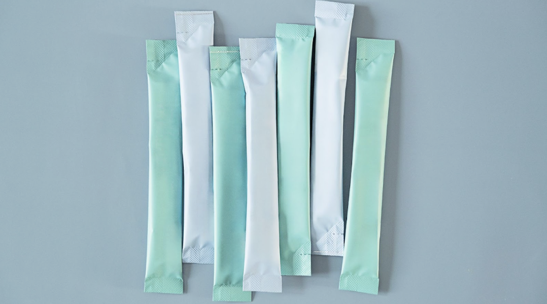 數條淺藍色與淺綠色的條狀粉末包裝袋在灰色底色上交錯垂直排列