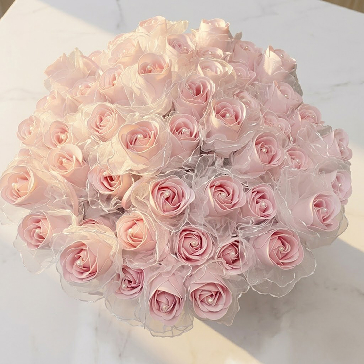 在明亮的自然陽光下，一大束粉粉嫩嫩的粉紅色肥皂花玫瑰，整齊地擺放在純淨的白色大理石紋桌面上，背景呈現柔和的室內光影。