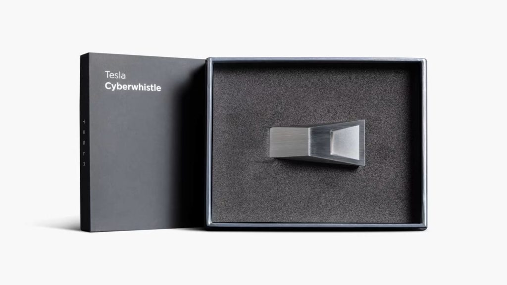 Tesla Cyberwhistle 開盒展示，銀色不鏽鋼哨子嵌於深灰色泡棉內襯中，搭配印有「Tesla Cyberwhistle」字樣的霧黑精裝盒，呈現收藏級包裝質感。