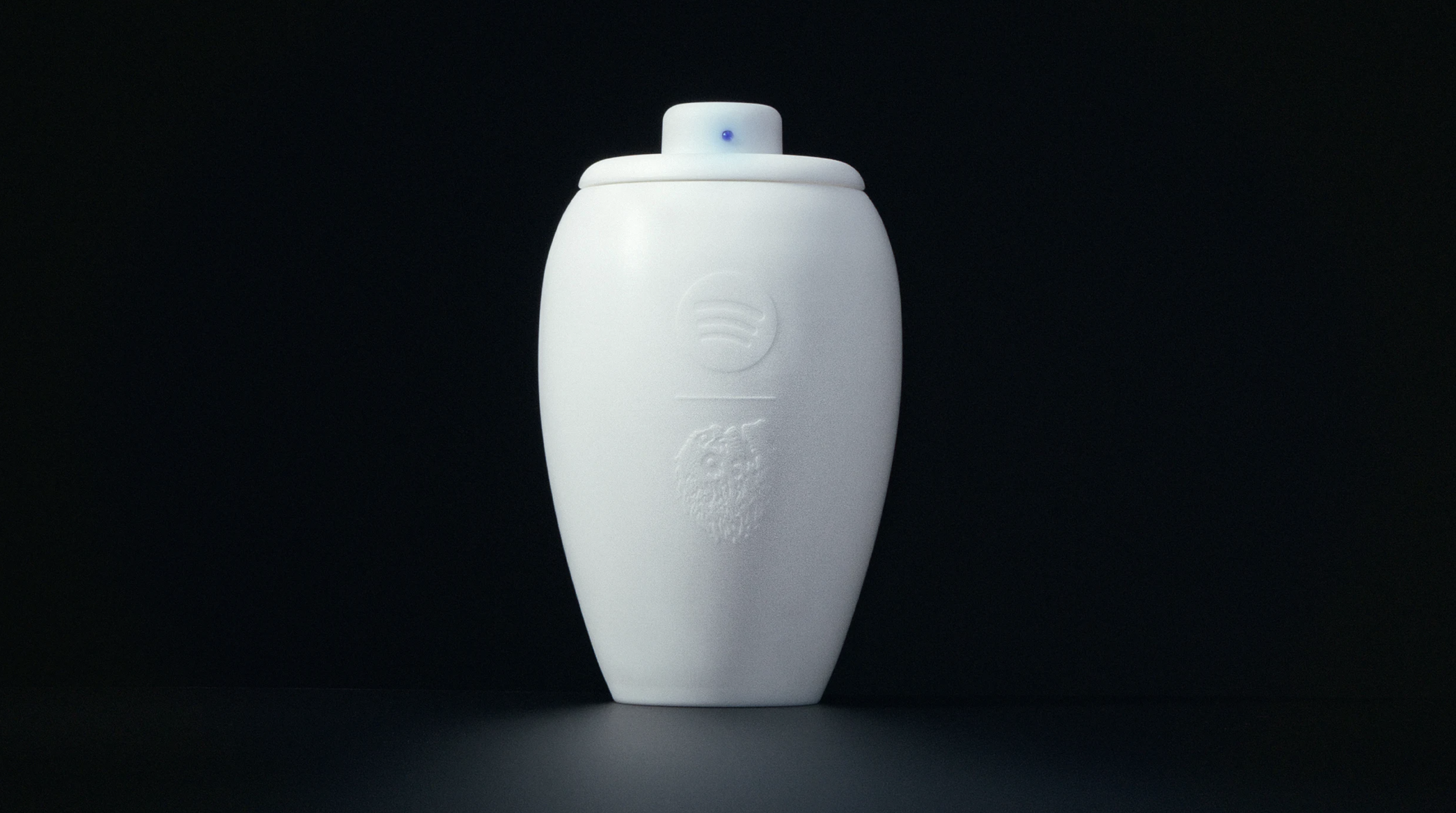 Spotify x Liquid Death 聯名「Eternal Playlist Urn」限量骨灰罈，白色鋁合金外殼，瓶身浮雕 Spotify 圓形 Logo 與 Liquid Death 骷髏圖案，蓋頂內建藍牙音響，發出藍色指示燈光。