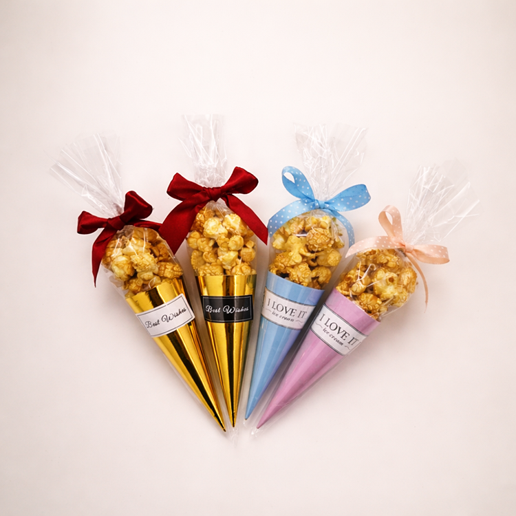四支不同顏色的「愛的爆爆」爆米花甜筒呈扇形排列，包含華麗金、夢幻粉與清新藍色包裝，搭配精緻蝴蝶結與客製化貼紙，展現繽紛豐富的視覺感。