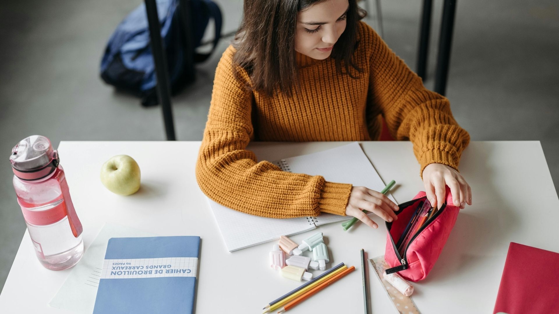 在學校的課桌上整理鉛筆盒