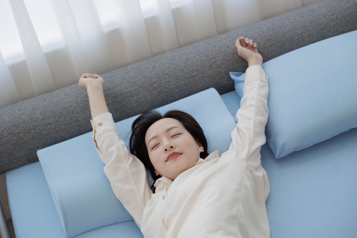 女性在森好眠吸濕排汗乳膠床墊上愉快伸展起床