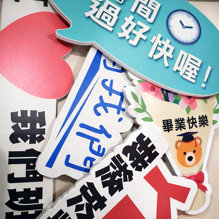「畢業拍照手舉牌，多款彩色紙板道具，包含對話框、愛心、橫幅設計，文字有『我們班』『畢業快樂』『時間過好快喔！』，並有戴學士帽小熊與花朵、時鐘插畫，適合畢業典禮拍照打卡。