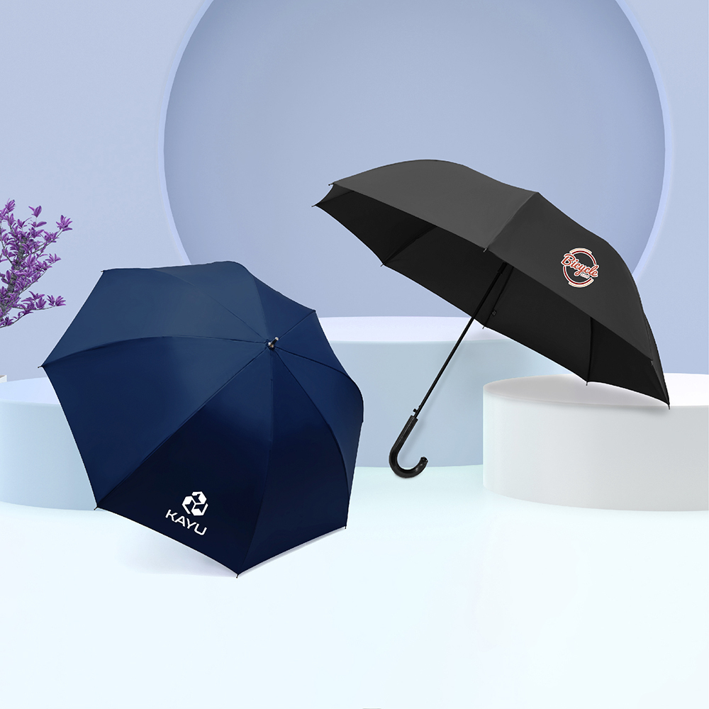 客製化雨傘展示，印有白色logo深藍色雨傘及印有彩色圖標的黑色彎把長傘，放置於簡約幾何展台上。