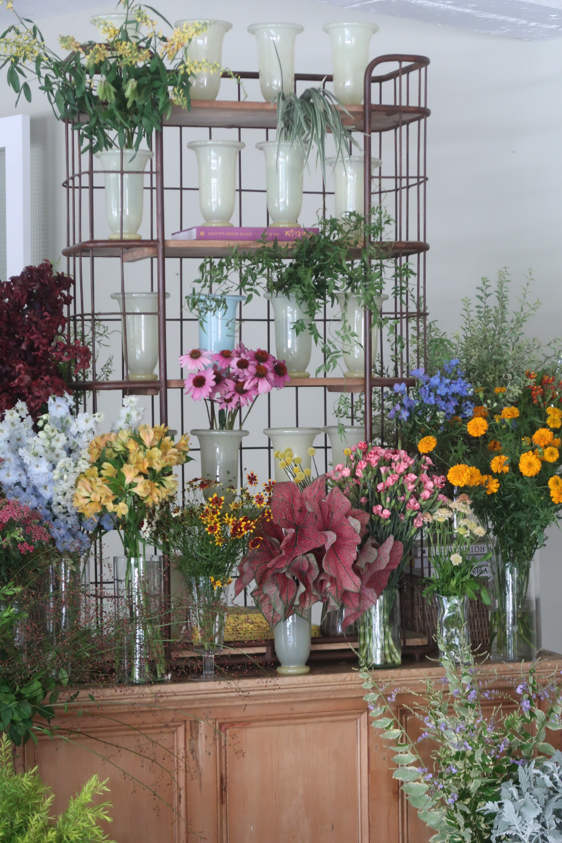 Salon flowers 花店備料現場，多個 HAY Empire 萊姆黃花瓶陳列於鐵網層架，前方擺放各色切花