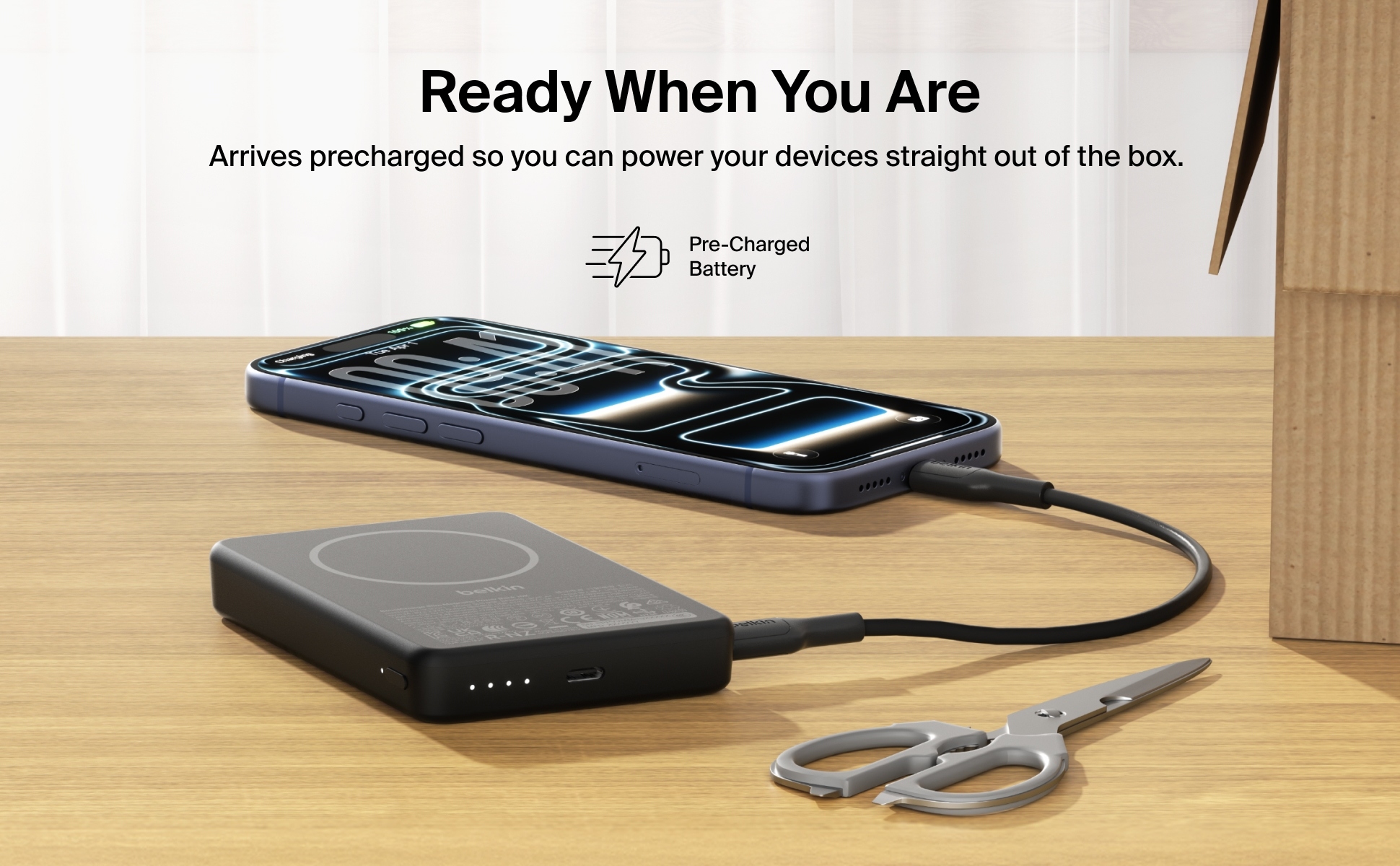Belkin BoostCharge Slim Magnetic Power Bank 10K with integrated kickstand charging an iPhone while connected to a USB-C cable