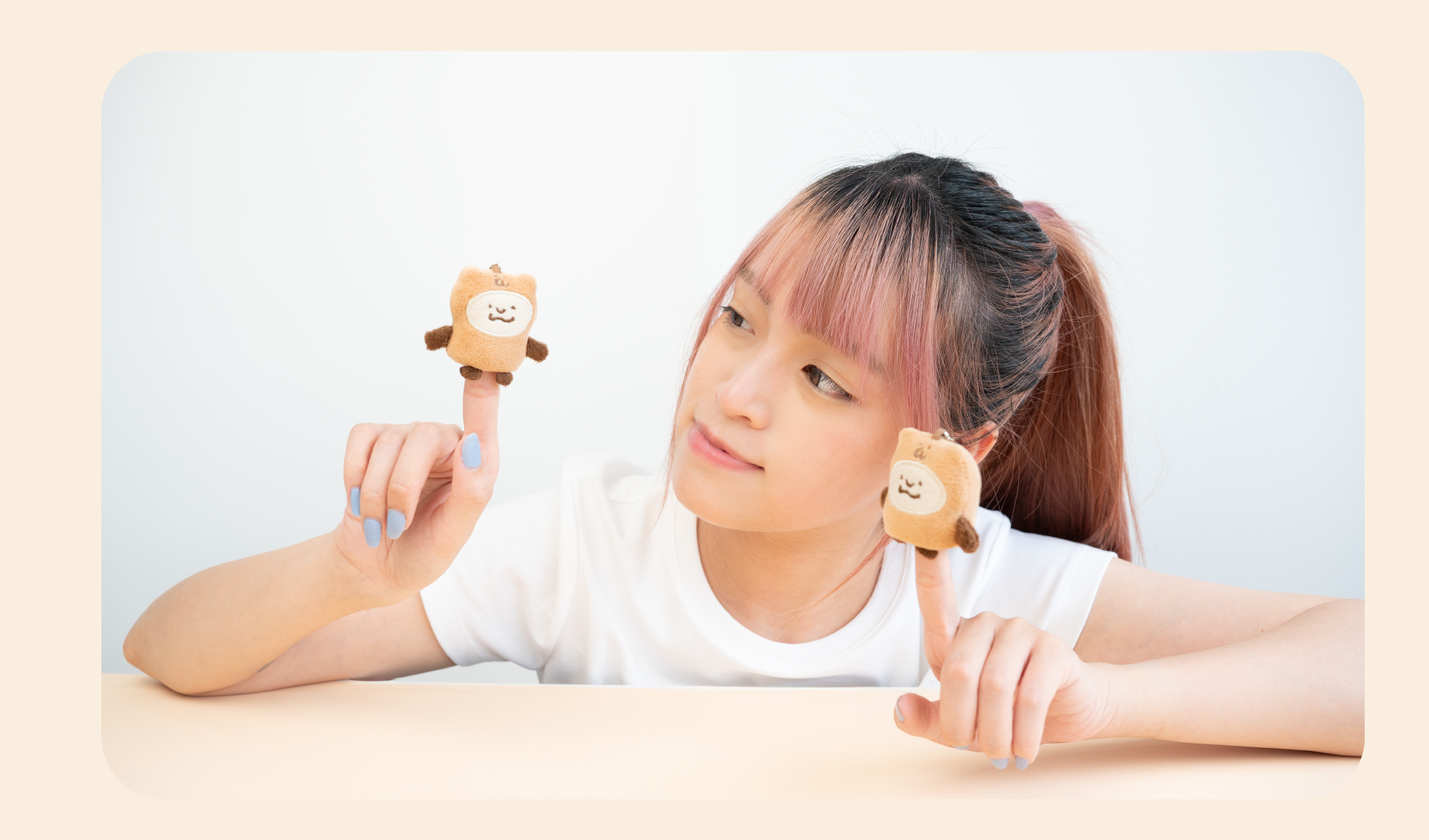小小PETIT × 咻咻熊聯名小小薯泥吊飾使用情境：女性雙手各頂起一隻咻咻熊布偶吊飾，指甲塗有聯名色「懶懶時光」暖藍色水性指彩，展現可愛互動與收藏感，適合送禮與自用。