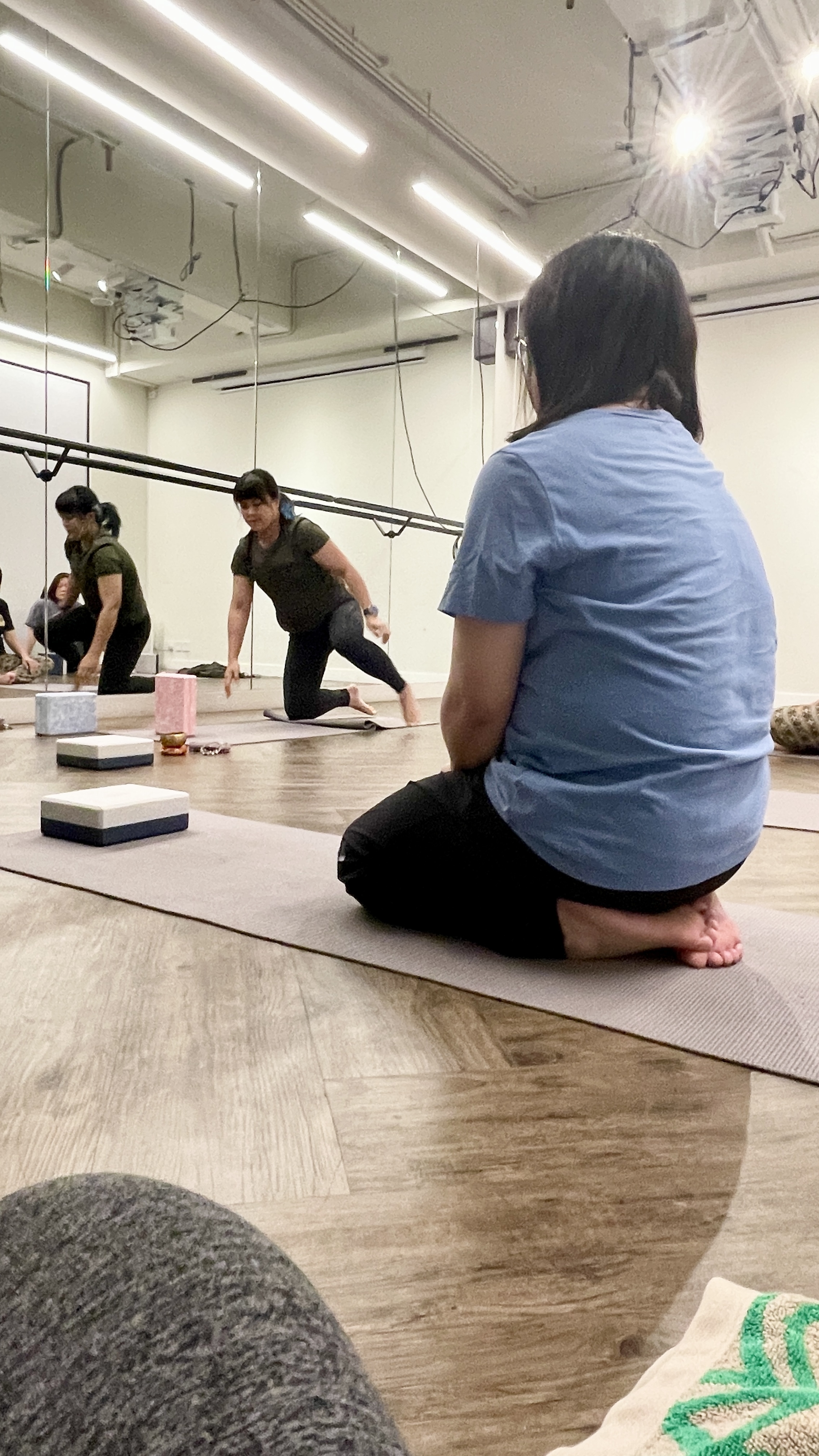 Natalie Chan, our yoga tutor is facilitating a guided yoga session,  & yoga student is concentrating on learning