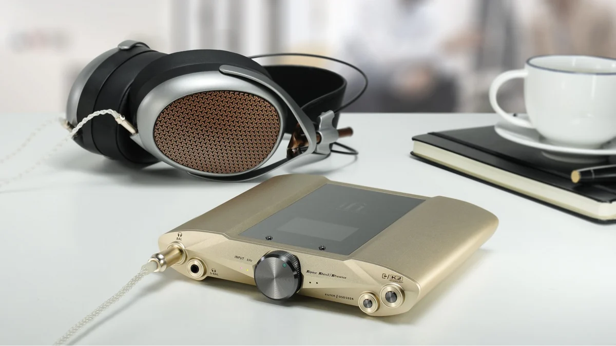 iFi Audio iDSD Valkyrie Bluetooth DAC Audio equipment on a desk with a tablet displaying music app.
