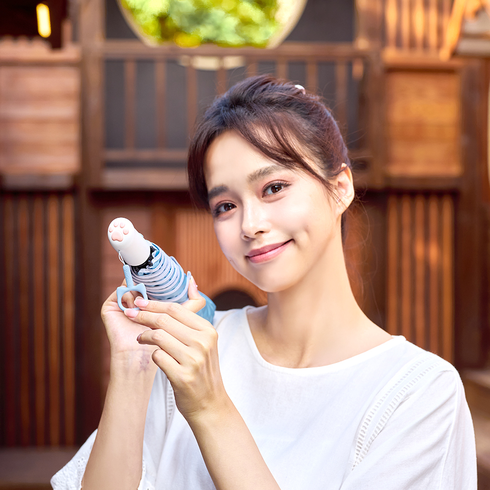 一位年輕女性笑著展示貓掌自動傘
