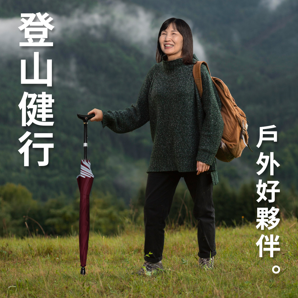 一位背著雙肩背包的女子在草地上健行,右手扶著一把酒紅色的登山輔助直傘