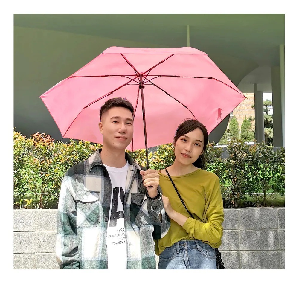 一對男女站在花圃前一起撐著粉色自動折傘