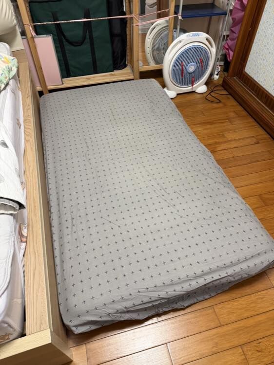 LOVEFU 大島樂眠無光厚墊使用者實拍：三摺厚墊套著灰色床包鋪在木地板上，放在床邊當備用床位