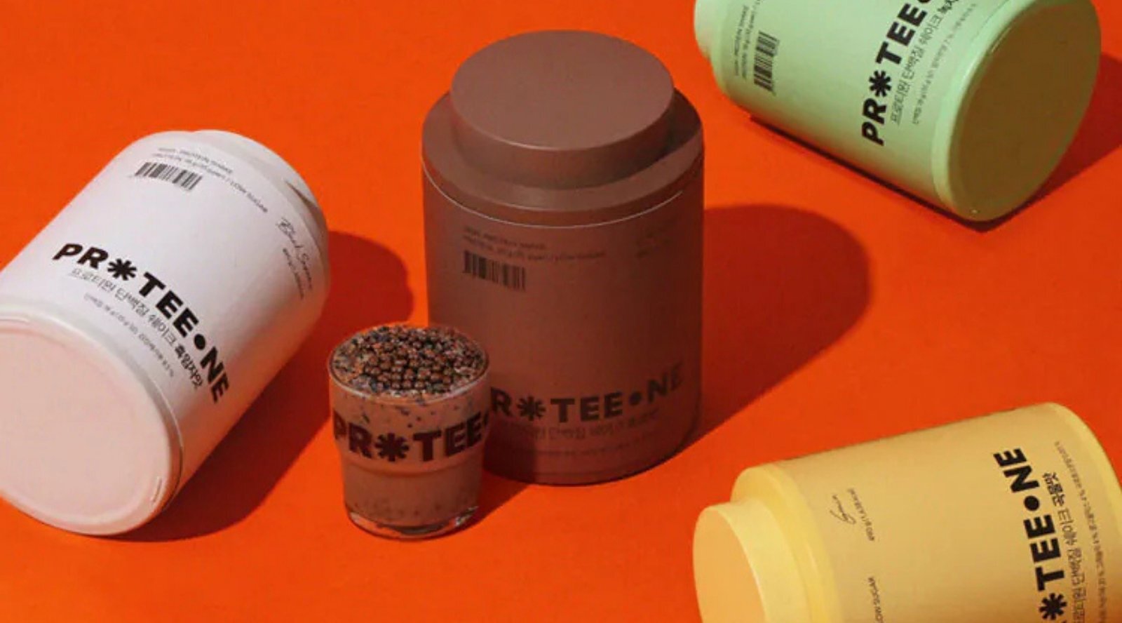 PROTEEONE 三罐高蛋白代餐並排放在橙色背景上，旁邊是穀物球與蛋白飲