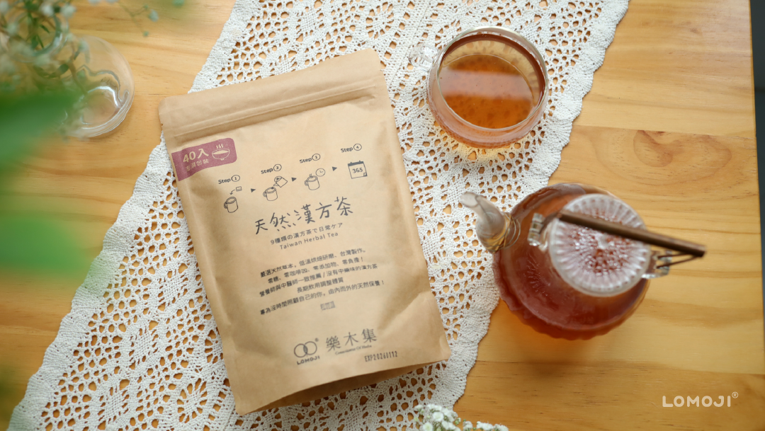 樂木集天然漢方茶40入澎湃包開箱:牛皮紙夾鏈袋包裝標註零糖零咖啡因,擺放在白色蕾絲桌墊上,旁邊附有玻璃茶壺與琥珀色漢方茶特寫