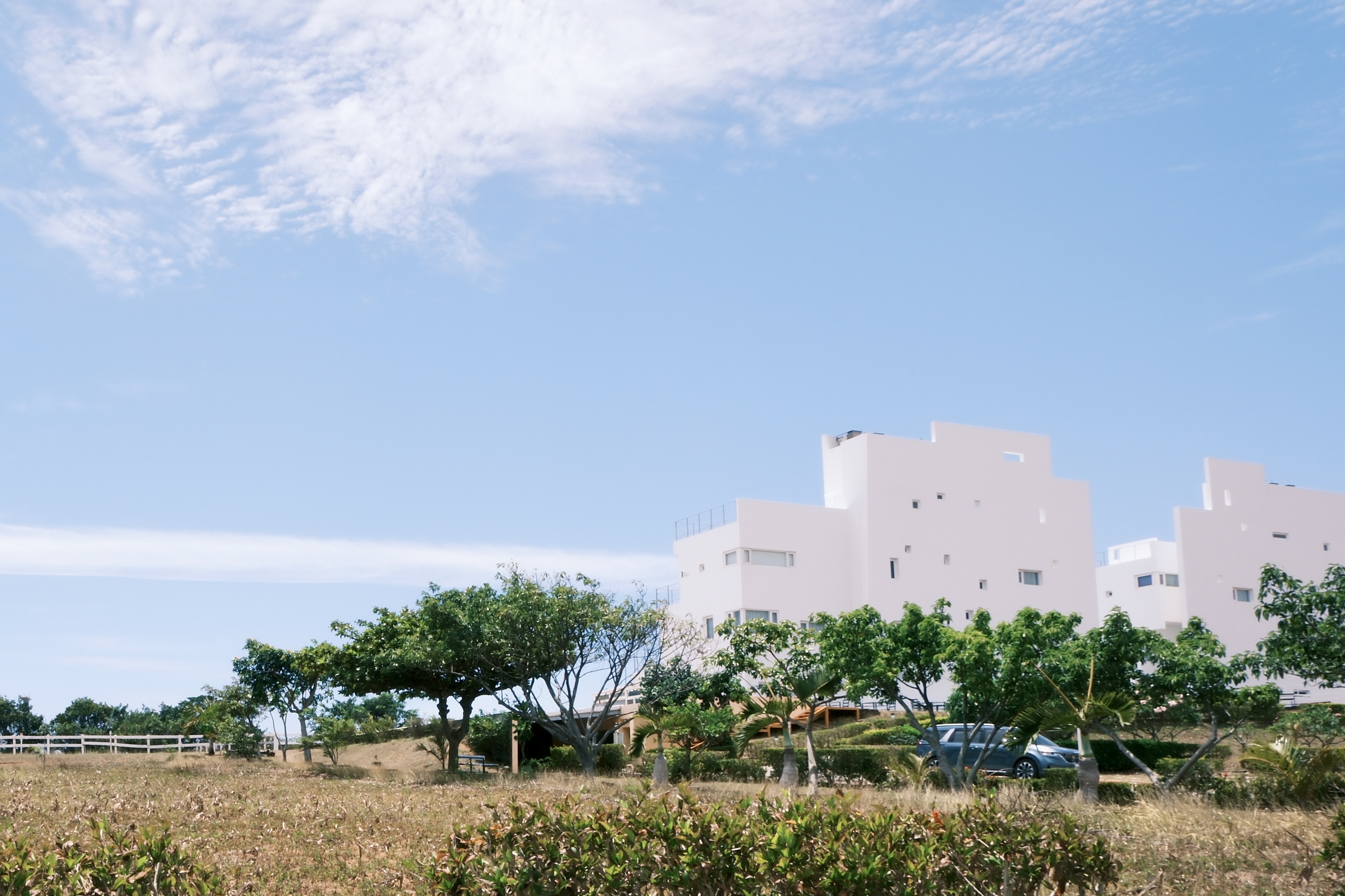 藍天、草地與遠方的白色建築物