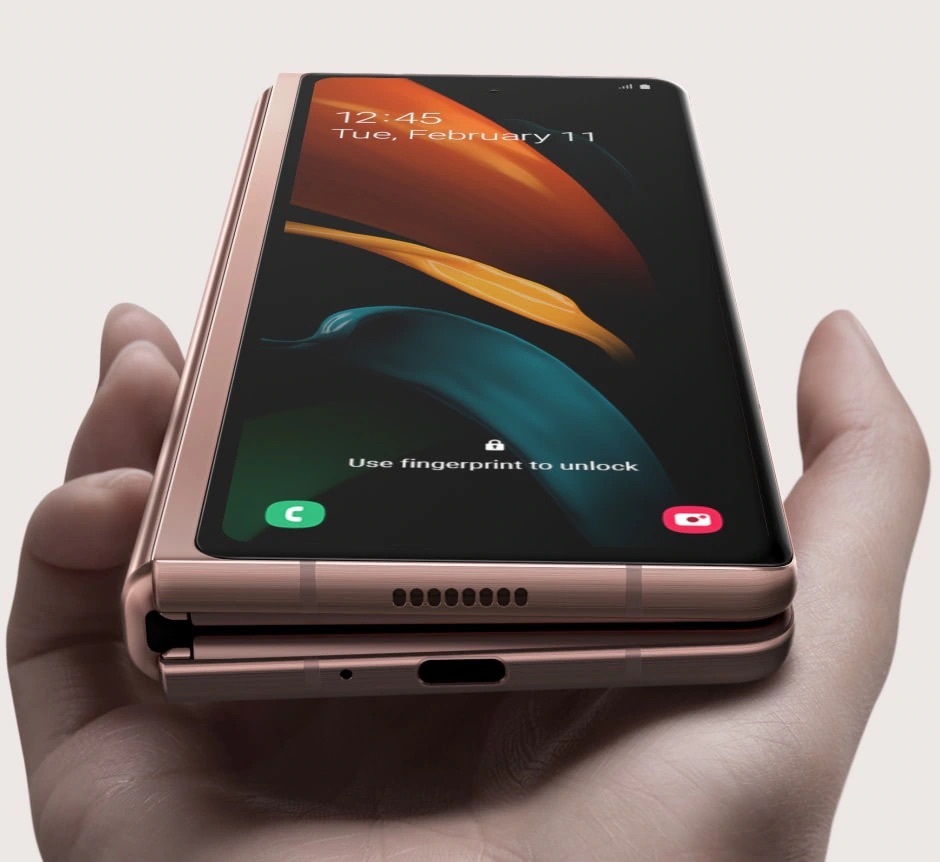 單手握持摺疊狀態的 Samsung Galaxy Z Fold2 星霧金智慧型手機,展示封面螢幕與底部連接埠,強調符合人體工學的單手操作設計