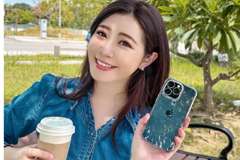 陳小八手持裝上極地冰岩殼的 iPhone，另一手拿著咖啡，背景為戶外綠地