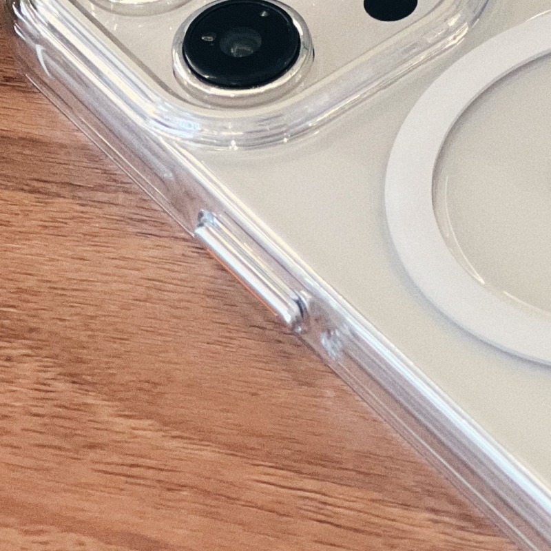 透明明岳殼 iPhone 側面特寫平放木桌，可見側邊的立體按鍵與加高邊框