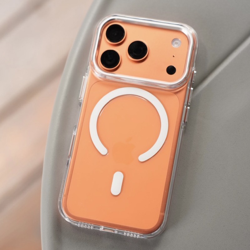 透明明岳殼包覆的橘色 iPhone 平放淺色桌面，背面白色 MagSafe 磁環清晰