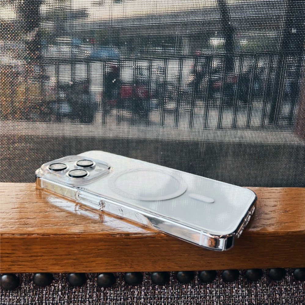 透明零手感 Lite Case 包覆的 iPhone 平放木質檯面，戶外光下殼身高度通透