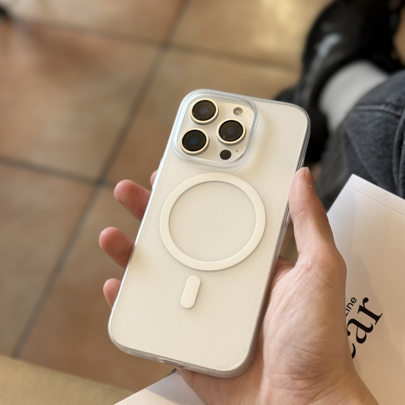 手持米白色磨砂超薄殼的 iPhone 俯視，背面 MagSafe 磁環清晰