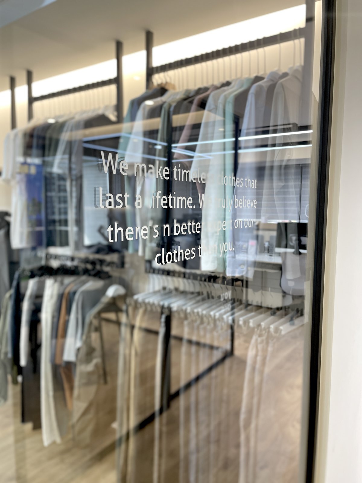 Showroom 吊掛陳列的當季服飾與玻璃上的品牌標語