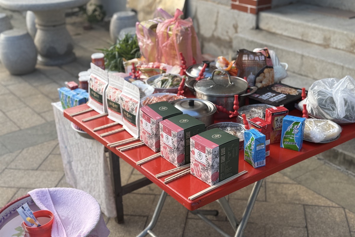 供桌上零食、罐裝運動飲料、蒜香雞球與兩口不鏽鋼湯鍋擠在一起，七月流火的濾掛盒與半磅包混在其中