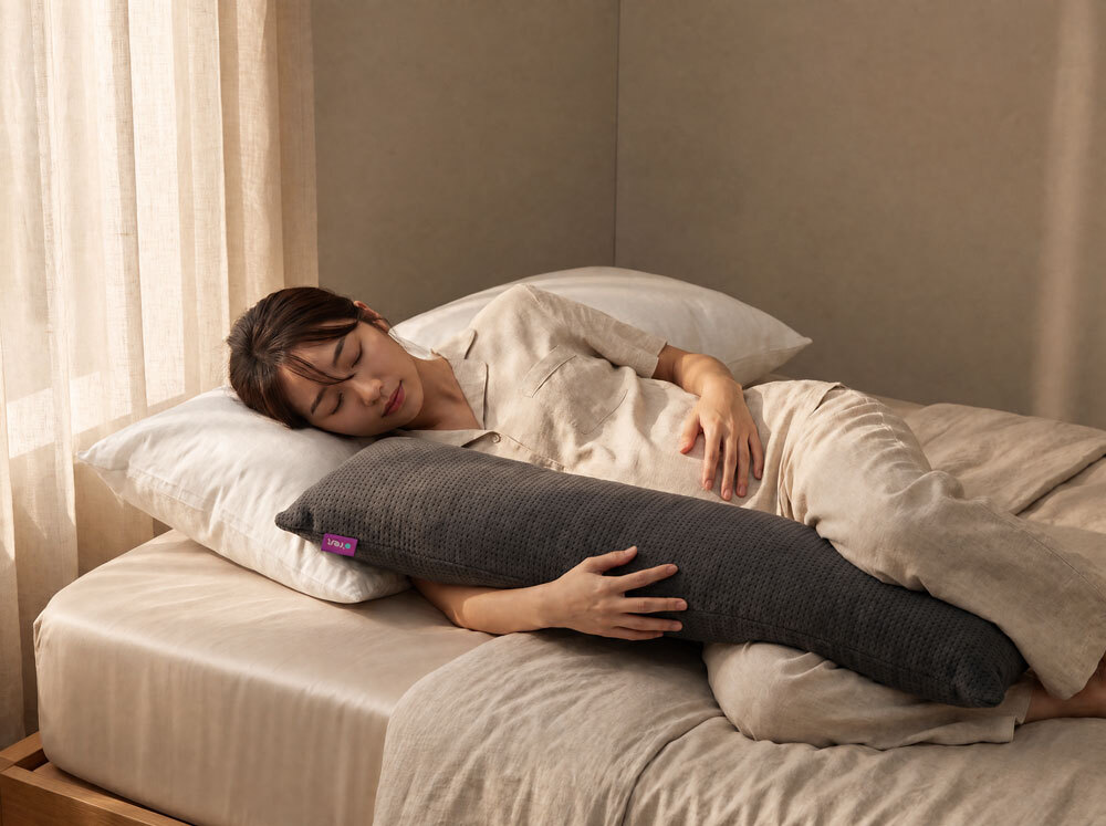 懷孕的女性側臥_長抱枕夾在她的雙膝之間