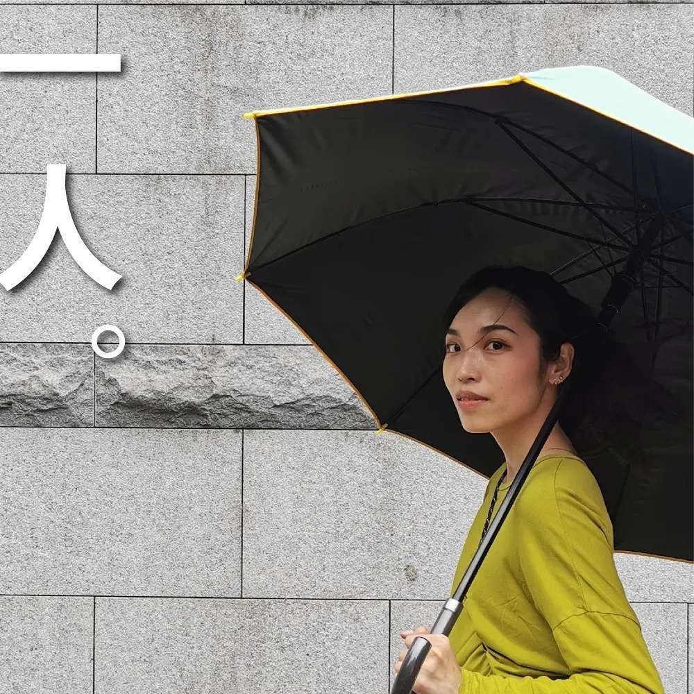 女子單人撐著藍色大顯威風長直傘,黑膠大傘面搭配醒目黃色滾邊