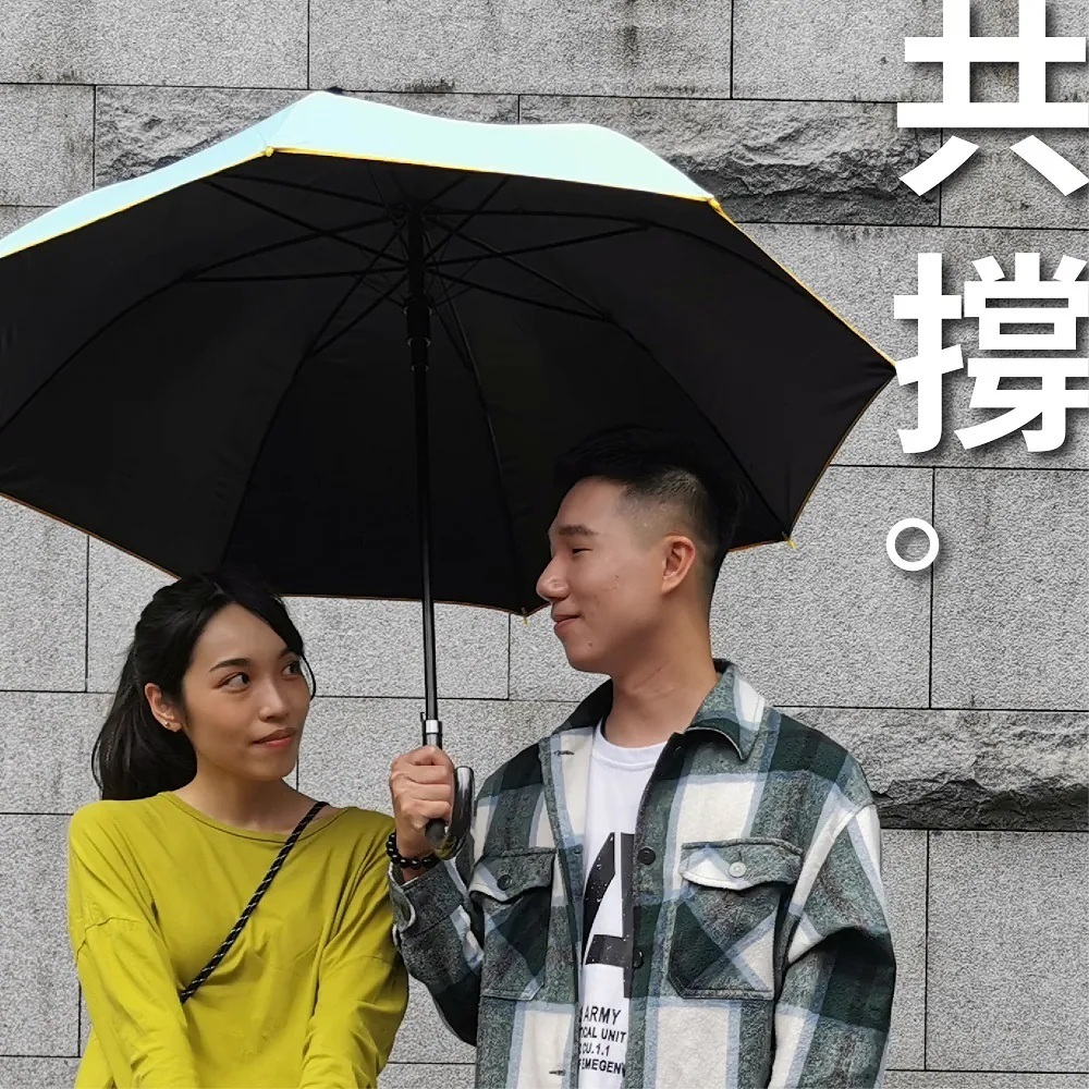 男女共同撐著藍色大顯威風長直傘,寬大黑膠傘面提供雙人遮蔽空間