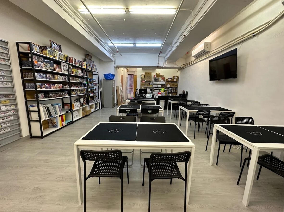 Interior view of ACard TCG retail store in San Po Kong Hong Kong showing tabletop gaming tables and card display shelves.