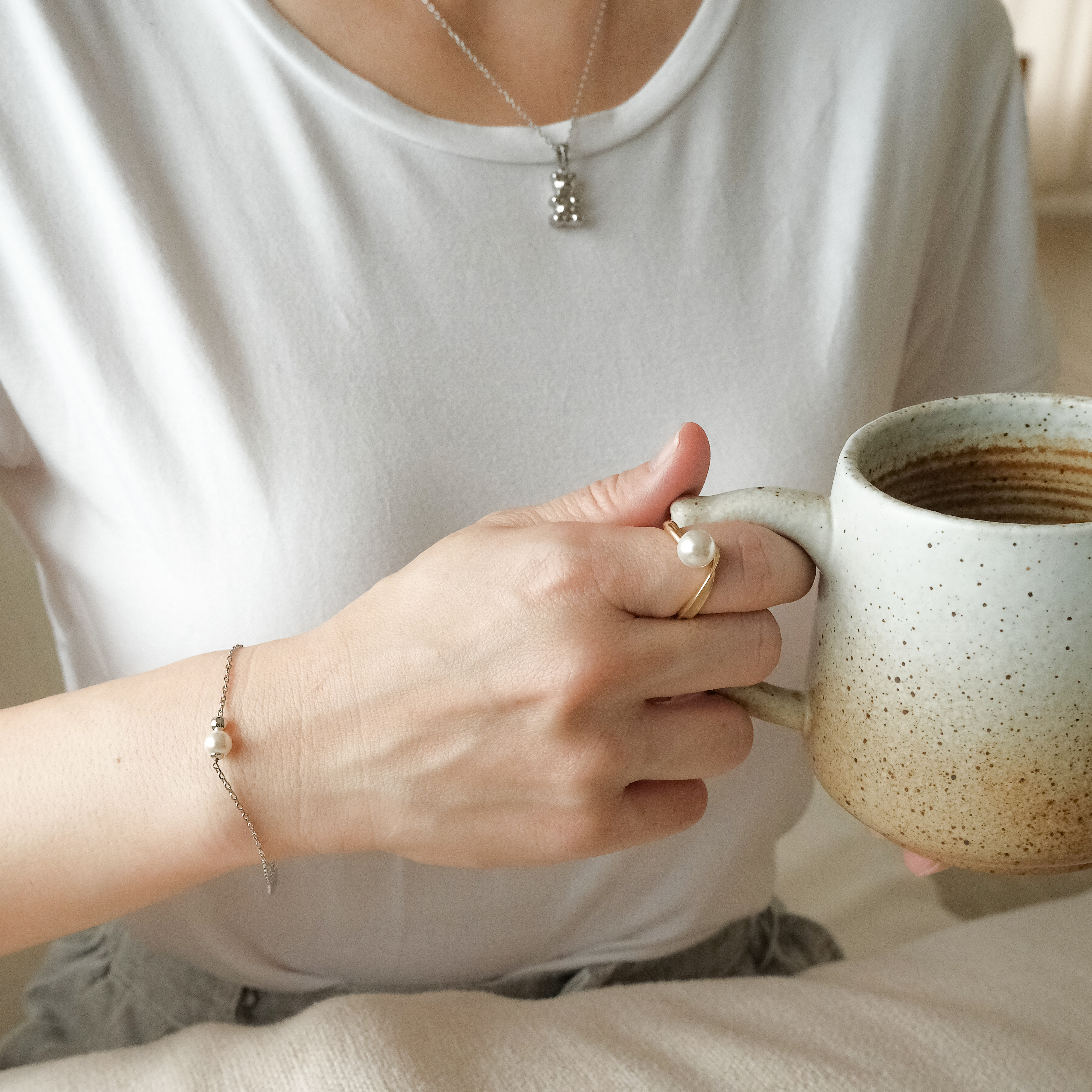 戴著珍珠手鏈、珍珠戒指,手拿咖啡杯的女子