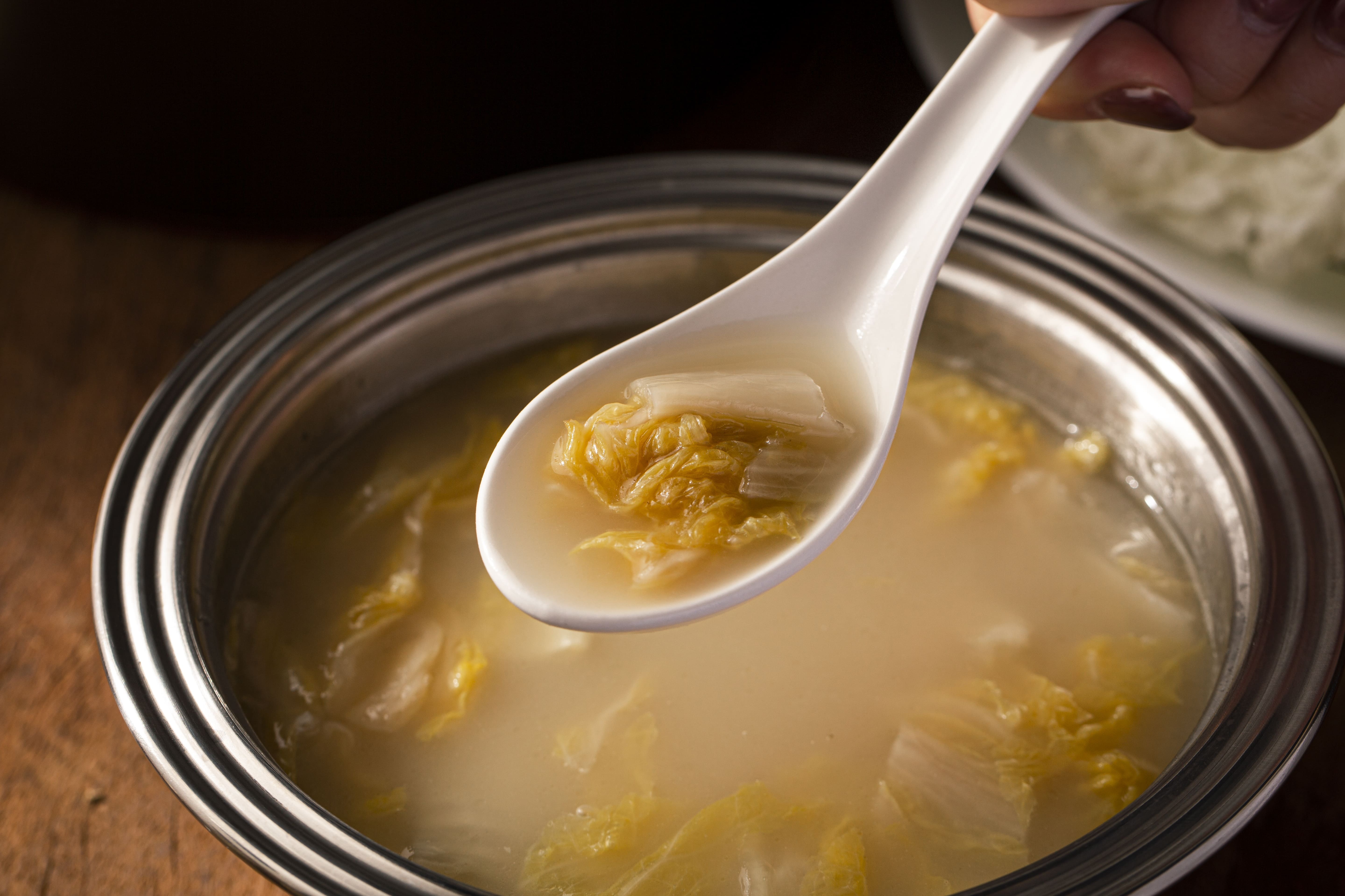 春水良品酸白菜湯，湯匙舀起酸白菜與湯汁