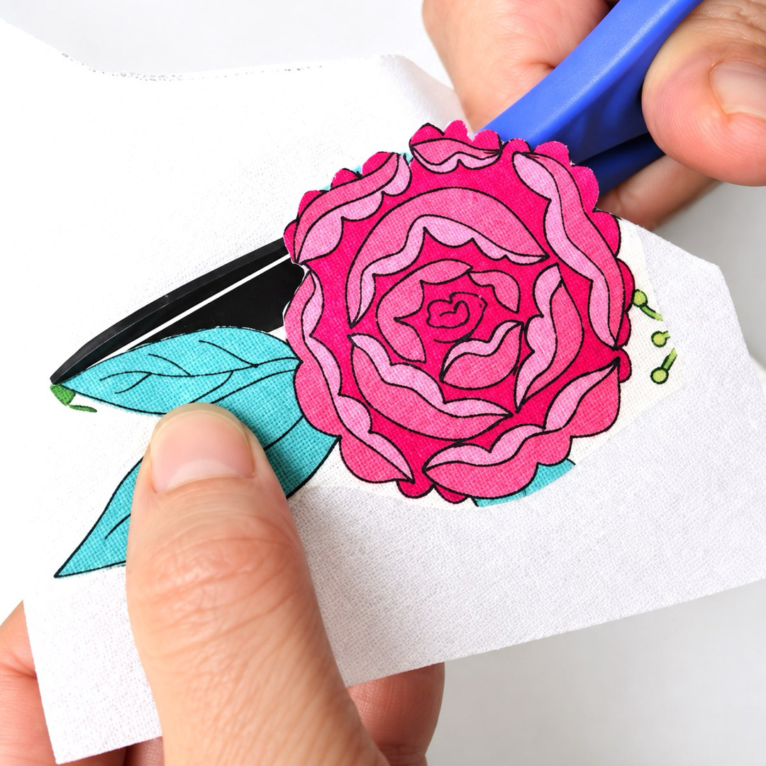 Small craft scissors trimming the outline of a flower and leaves