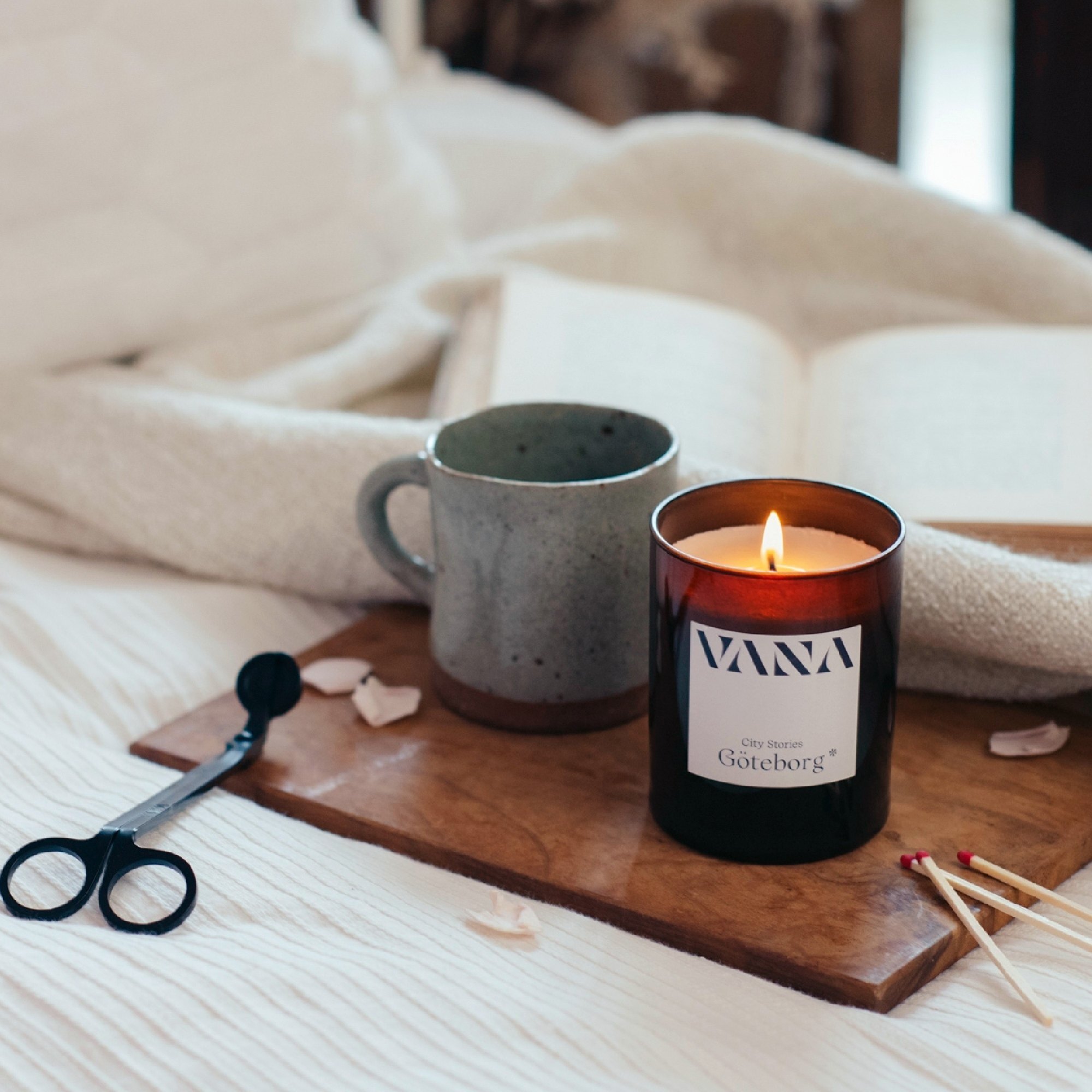床邊托盤上的 VANA 蠟燭、燭芯剪與火柴