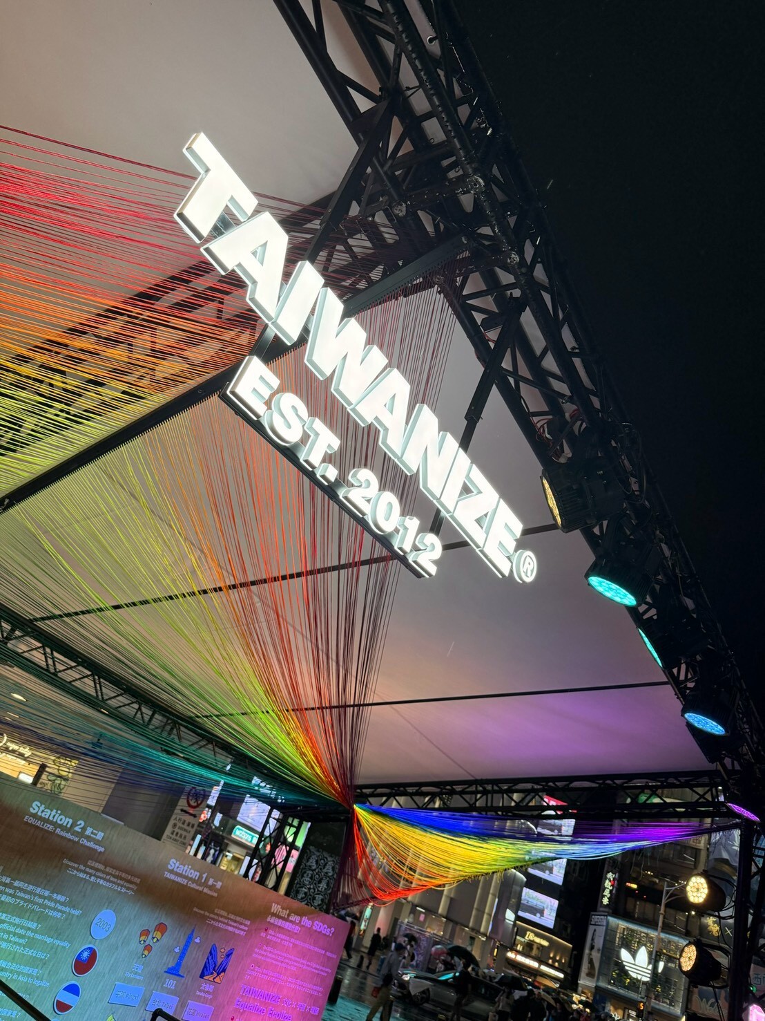 Illuminated TAIWANIZE sign beneath the pavilion’s rainbow canopy