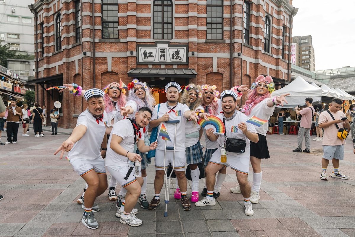 Participants in rainbow outfits posing together outside The Red House in Ximending