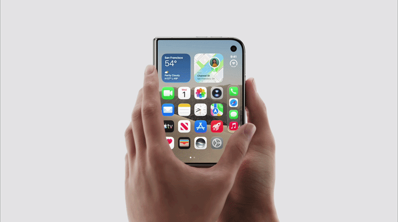 雙手持握摺疊式 iPhone Duo 展開後的螢幕畫面,機身為橫向展開的 4:3 比例大螢幕,右上角有圓形前鏡頭開孔,主畫面顯示天氣與地圖小工具及 App 圖示列(FaceTime、日曆、相簿、郵件、備忘錄、時鐘、Apple TV、App Store 等)。