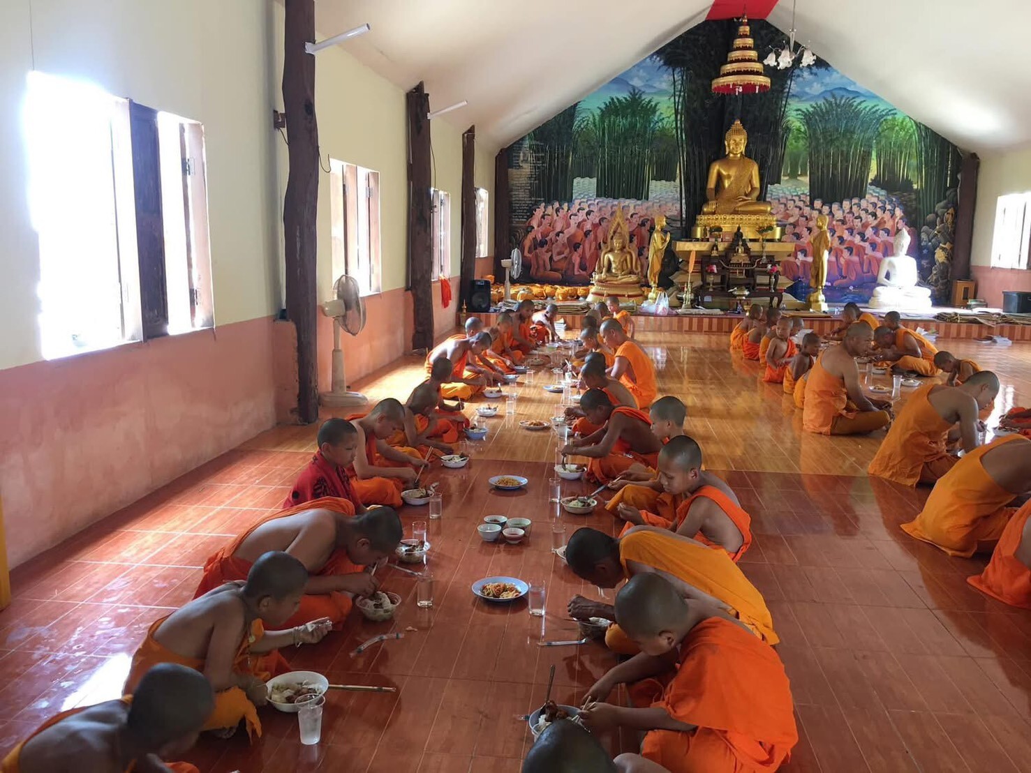 小沙彌在佛堂內共同用餐，後方可見金色佛像