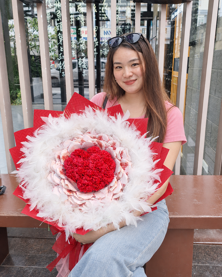 女生手抱大型紅色康乃馨香皂花鈔票羽毛花束