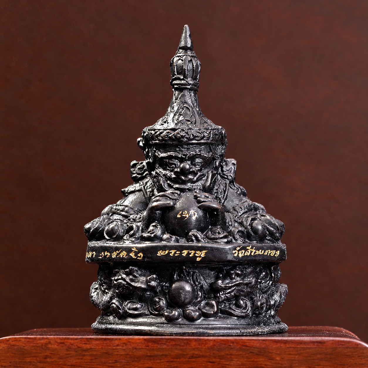 拉胡寺黑色拉胡天神供奉像正面,雙手持圓盤於口前,下方為圓形紋飾底座