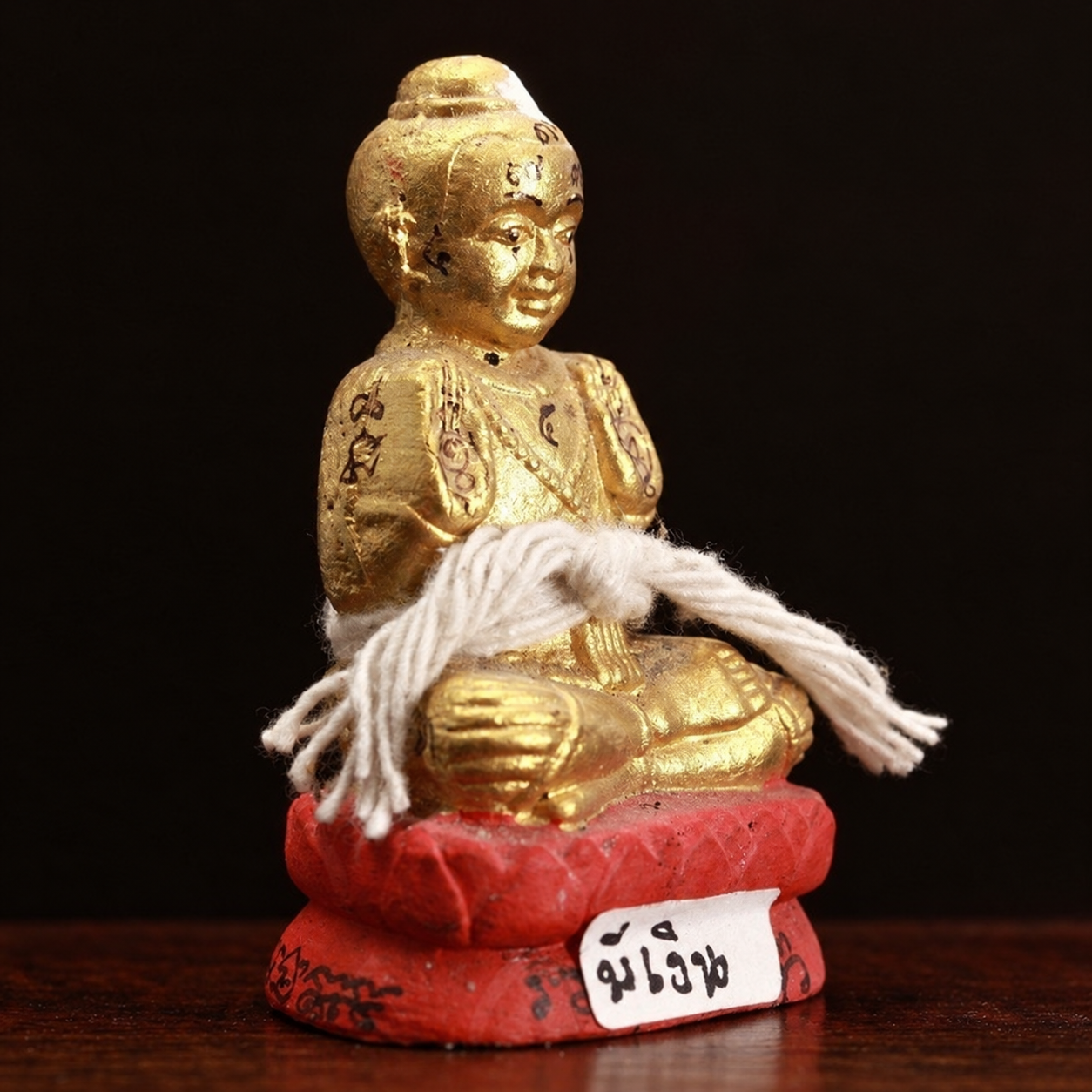 財寶搬運古曼童側面實拍,呈現金色童子身形、手臂符字、白色線繩與紅色蓮座
