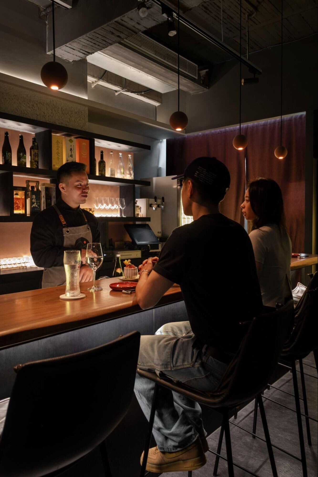 酒桃店長 Ian 在吧台內與客人互動的工作照