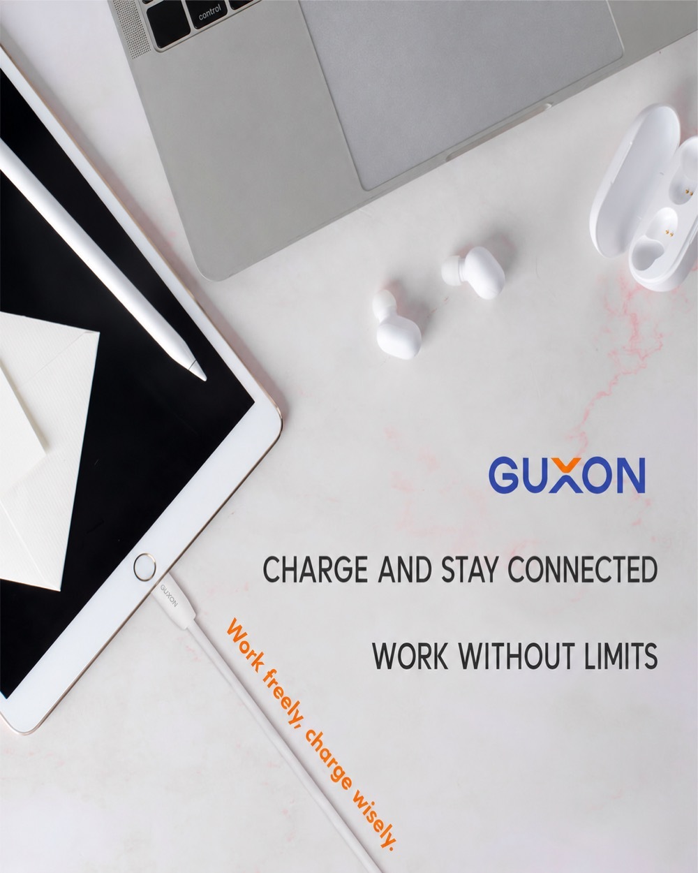 GUXON cable charging a tablet on a desk alongside a laptop and earbuds