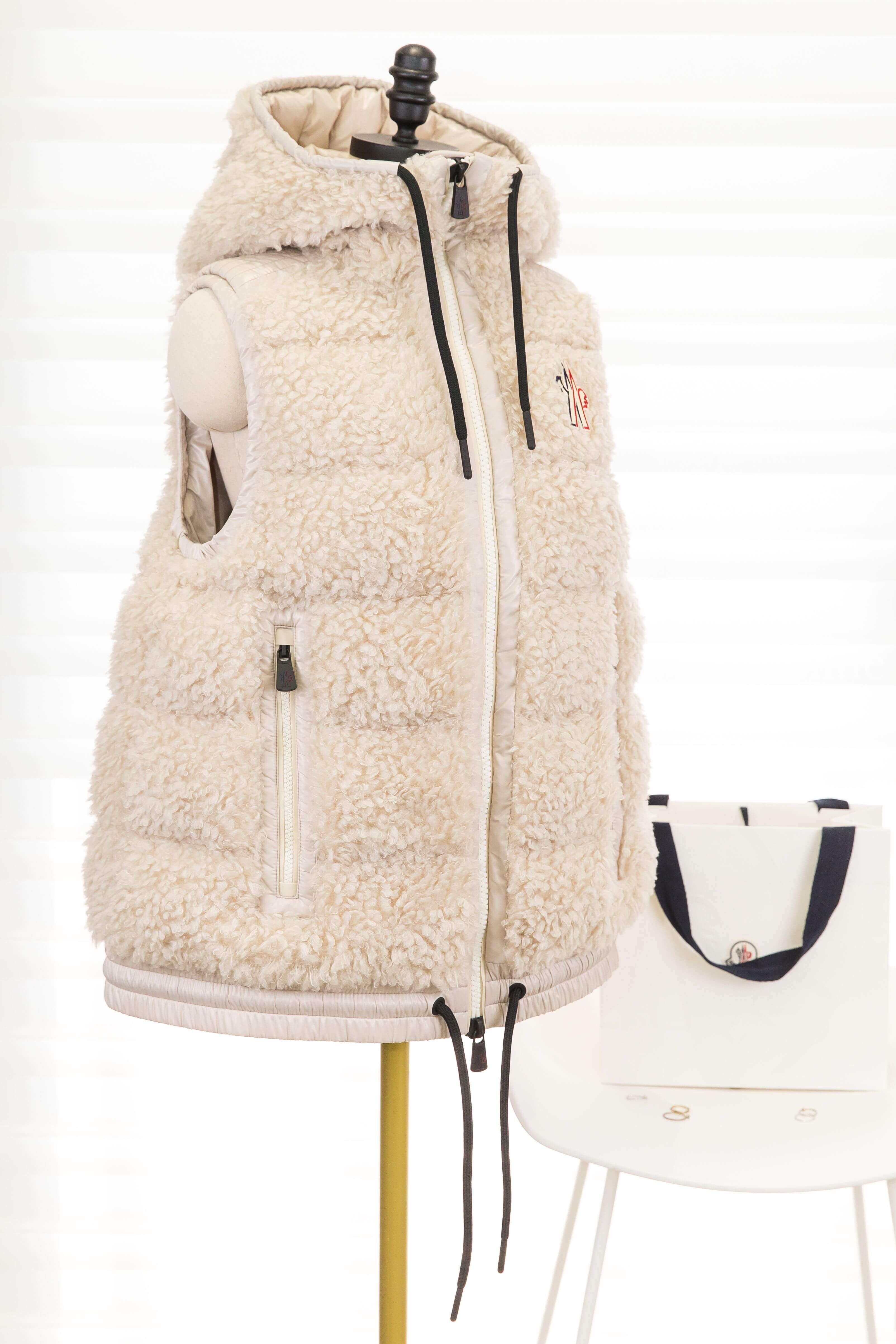 Moncler Teddy Hooded Insulated Gilet 淺米色滑雪系列泰迪絨連帽羽絨背心，斜側角度展示泰迪絨質感、連帽與拉鍊口袋