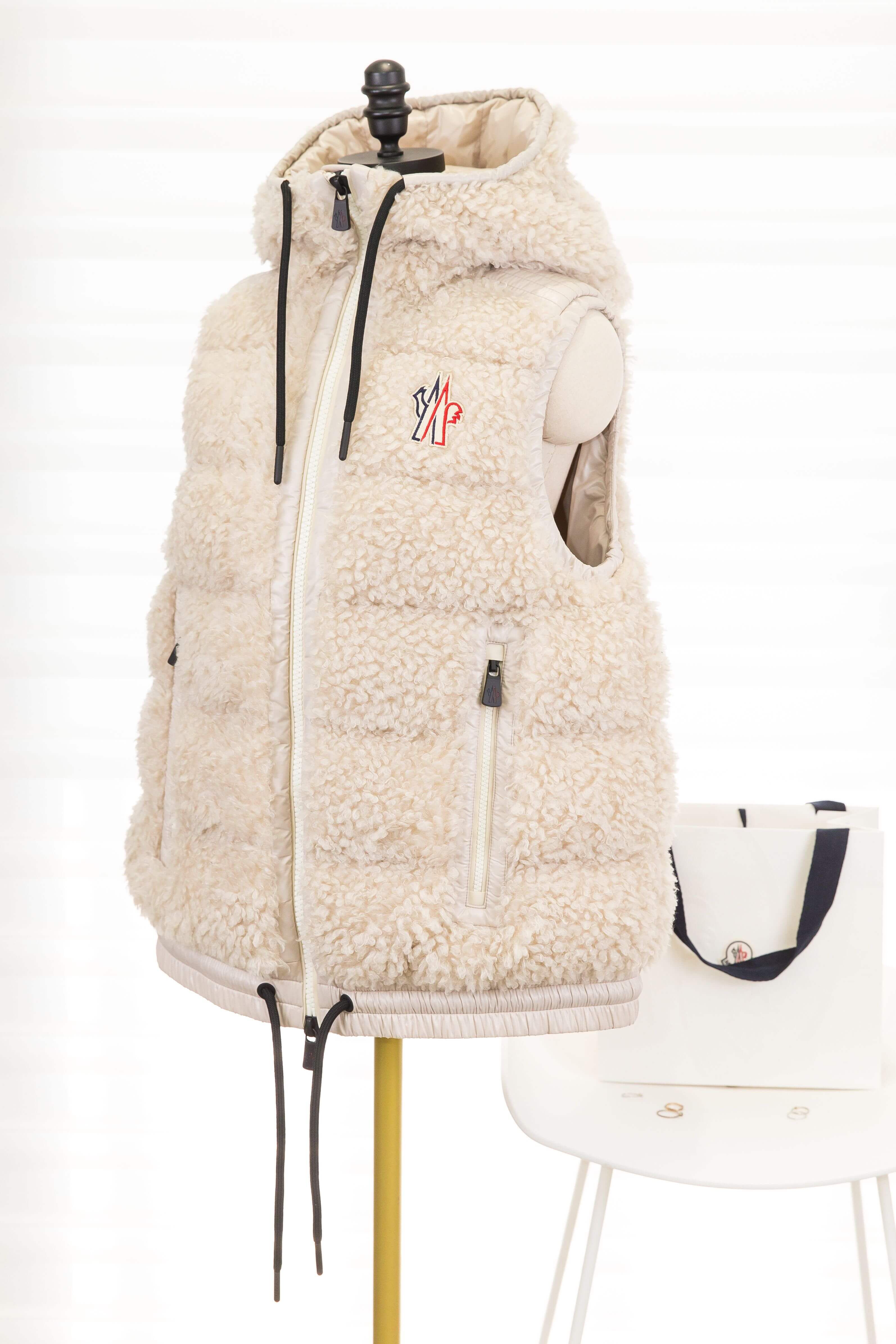 Moncler Teddy Hooded Insulated Gilet 淺米色滑雪系列泰迪絨連帽羽絨背心，另一側斜角展示胸前Logo、帽型與無袖版型