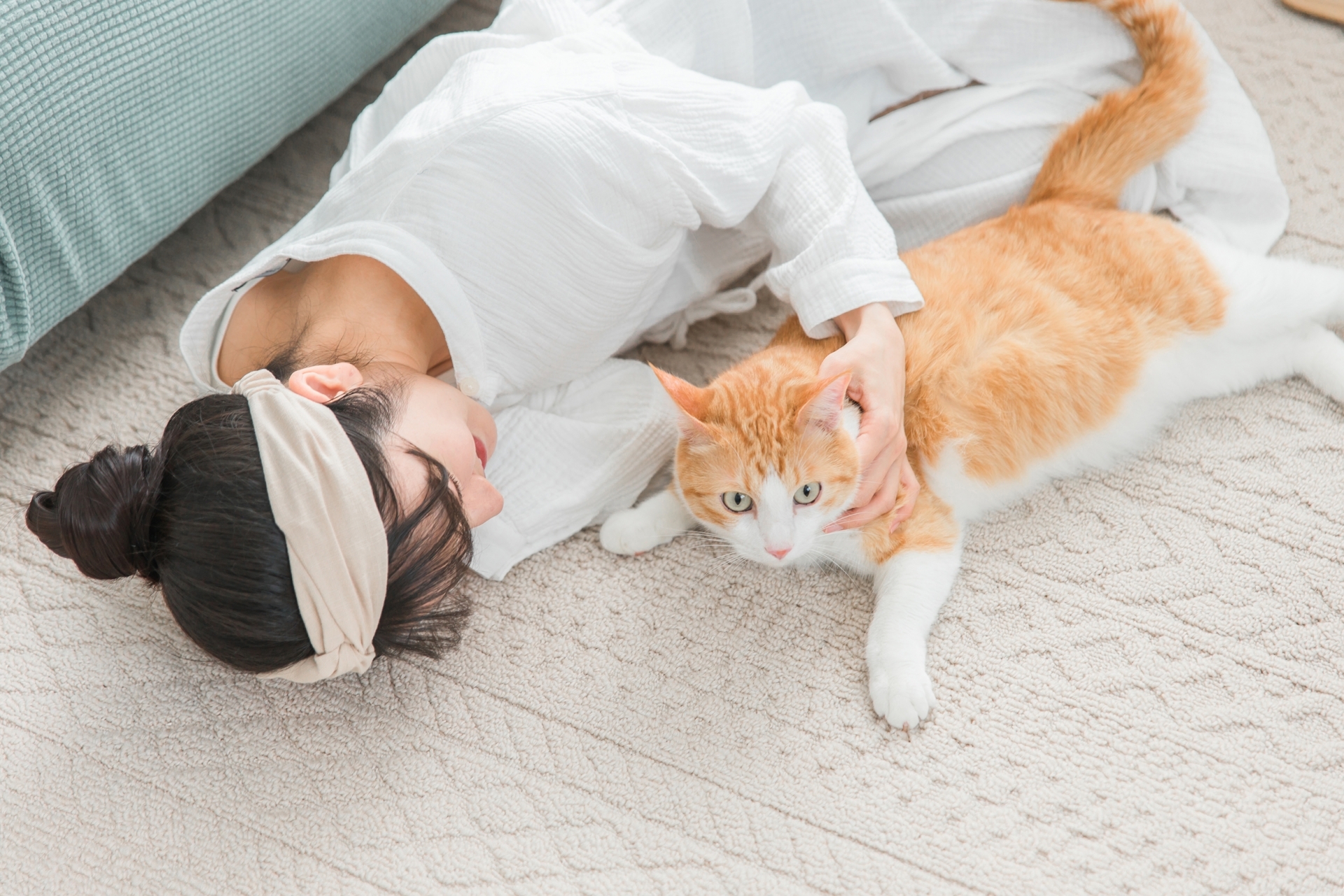 飼主躺在地毯上陪伴貓咪