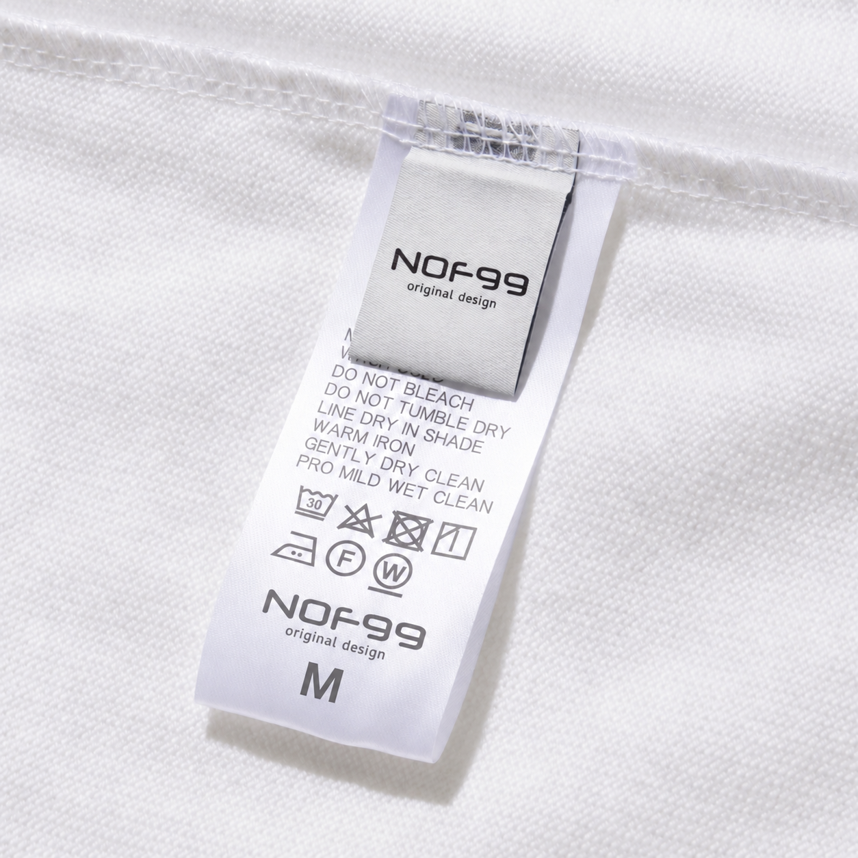NOF99 白色衣服洗滌標籤近拍,洗標標示不可漂白與30度洗滌